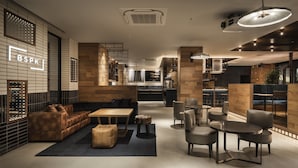 A modern interior with a leather sofa, round tables, and a bar area. - Bespoke Hotel Shinsaibashi (Osaka)