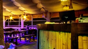 A dimly lit restaurant with tables and chairs arranged under a canopy. - Hotel Ruby Arena (Thiruvananthapuram)