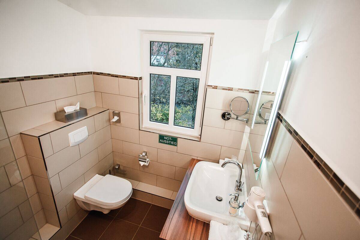 A compact bathroom with a toilet, bidet, sink, and a window.