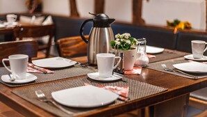 A dining table set for four with white plates, cups, and a silver coffee pot. - Landhotel Kahltalmühle (Alzenau)