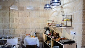 Un espace repas avec des murs en pierre, des tables blanches et des luminaires suspendus.