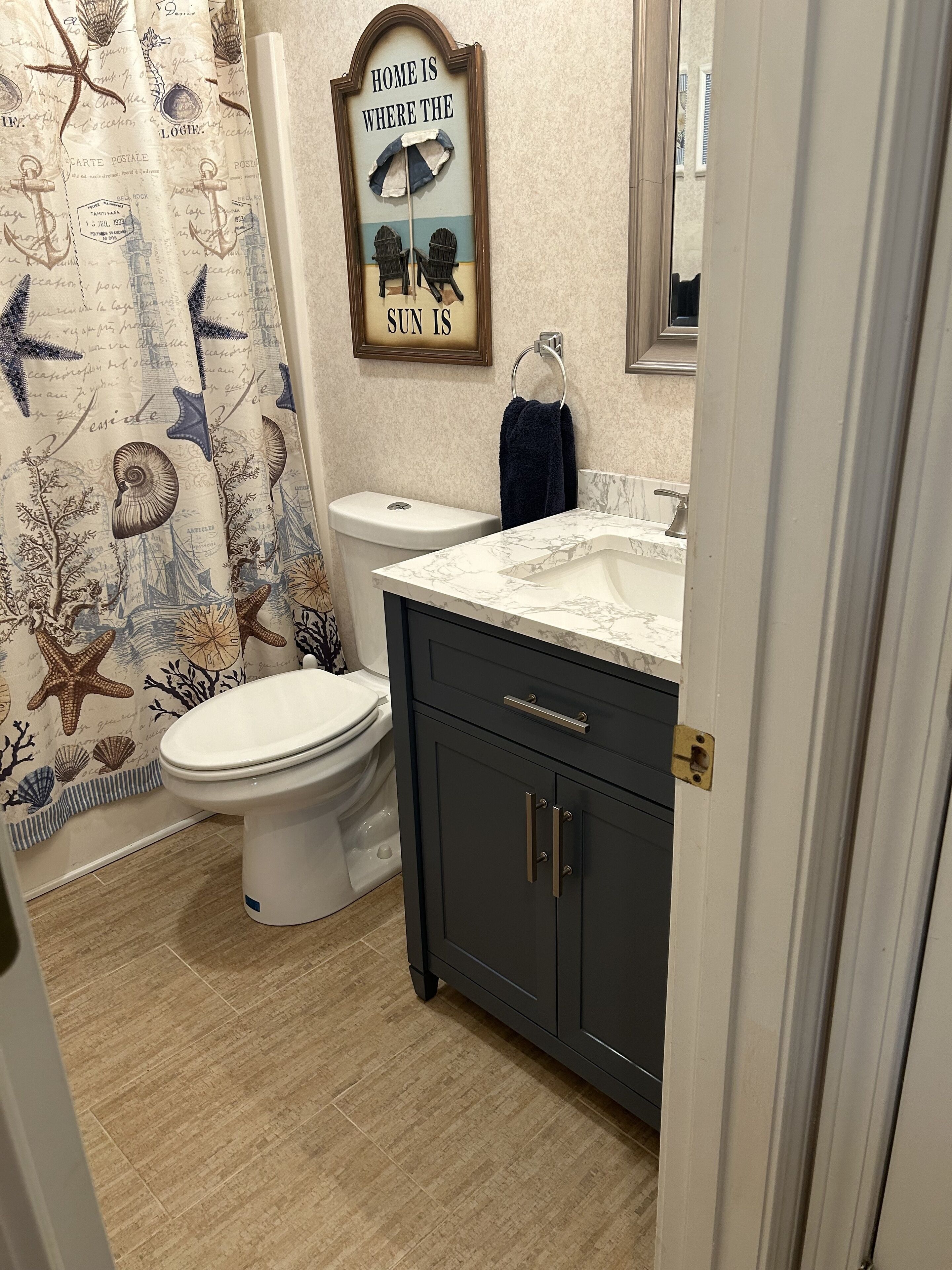 Un bagno con il water, lavandino e tenda della doccia con decorazioni a tema nautico.