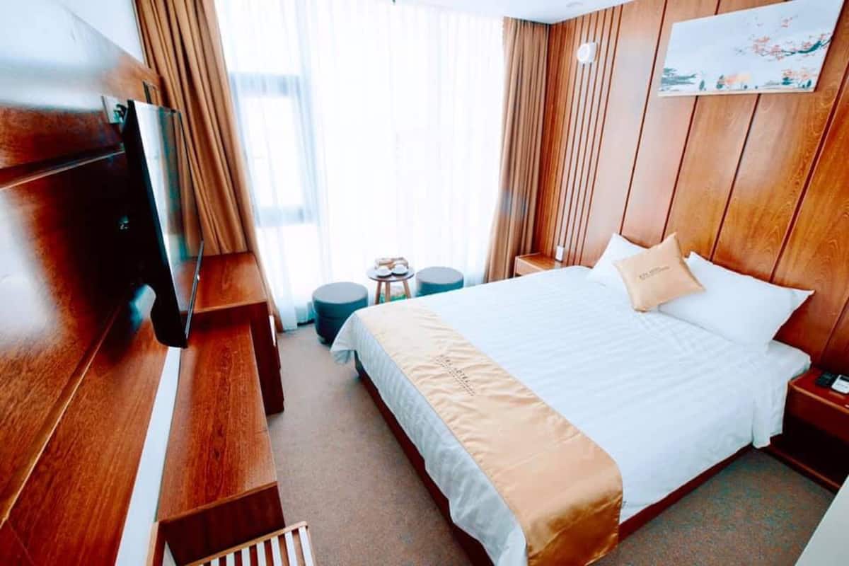 Une chambre d’hôtel avec un grand lit, un téléviseur fixé au mur, une petite table et une chaise.
