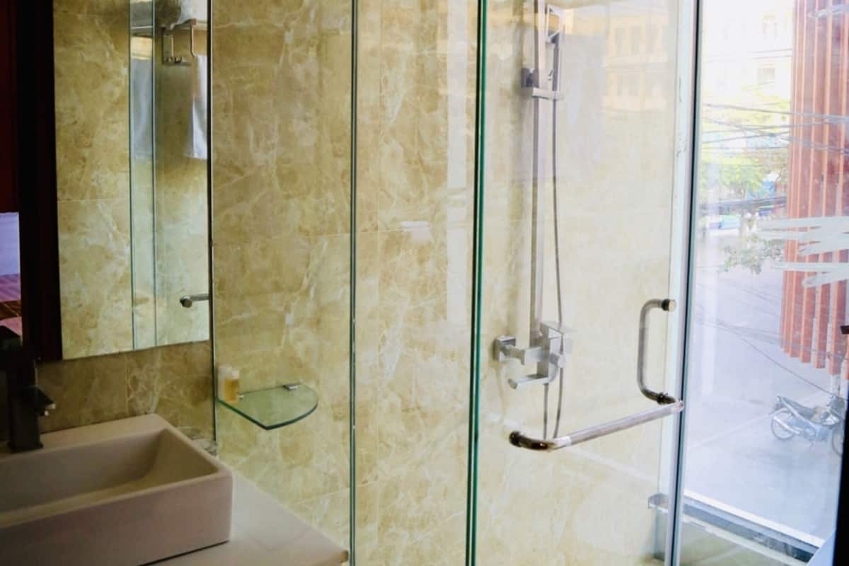 Une salle de bain moderne avec une douche en verre, un mur recouvert de carreaux de marbre et un lavabo blanc.