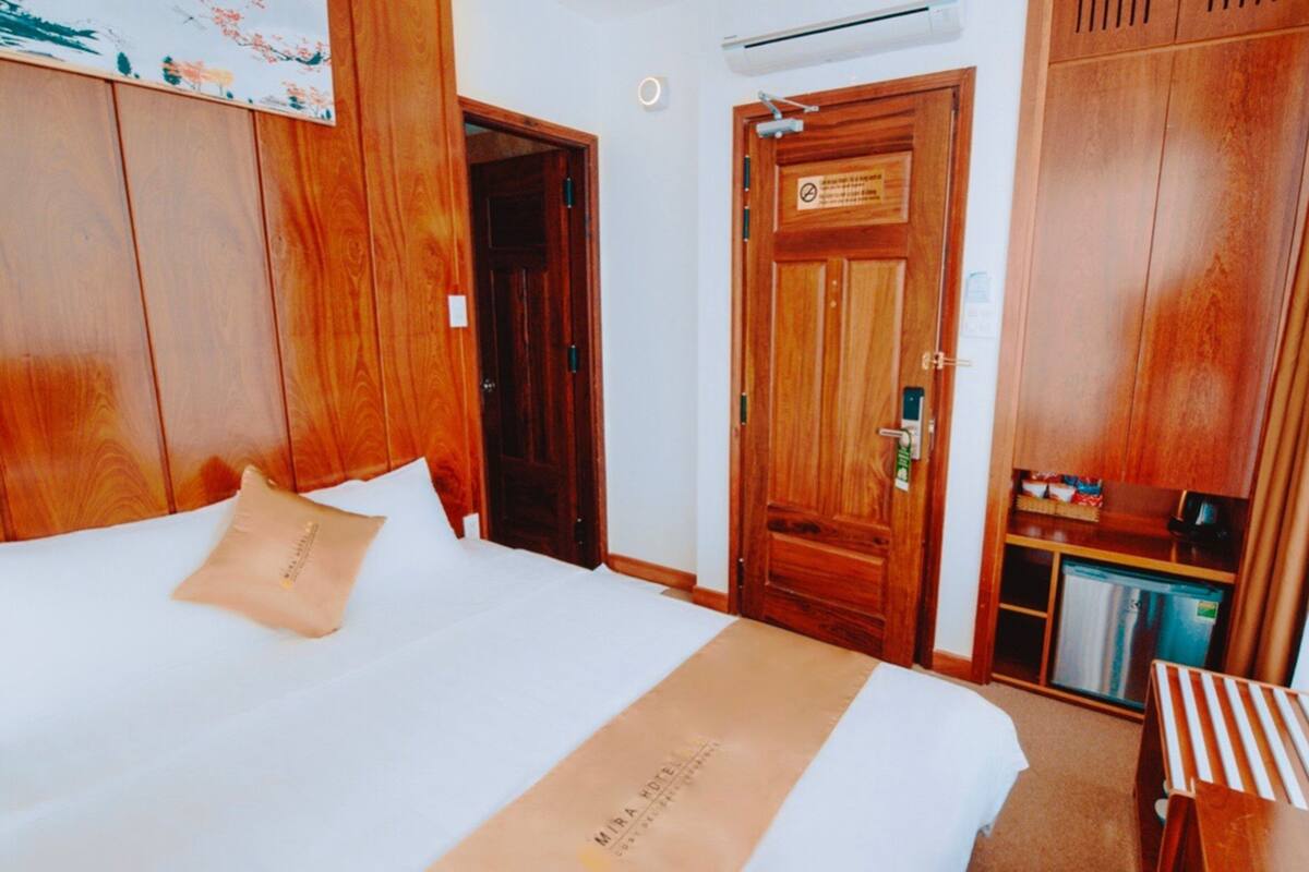 Une chambre d’hôtel avec un lit, une armoire en bois et une petite table avec une chaise.