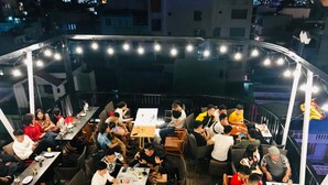 An outdoor dining area with multiple tables and chairs, surrounded by string lights. - Mira Hotel (Quy Nhon Nam)