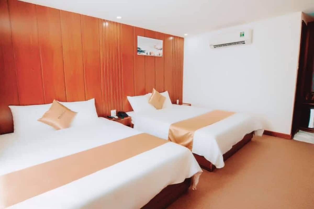 Une chambre d’hôtel avec deux lits, des lambris en bois sur les murs, un tableau accroché au mur et un appareil de climatisation.
