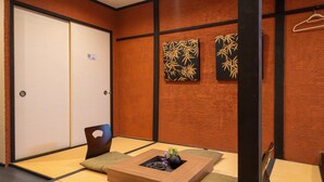 A traditional Japanese room with tatami flooring, a shoji screen door, and a low wooden table with a vase and decorative items. - NAKAZ Machiya , Osaka Umeda (Osaka)