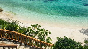 A beach with clear turquoise water, a sandy shore, and a wooden staircase leading down to the beach. - Parklane Bohol Resort and Spa (Anda)