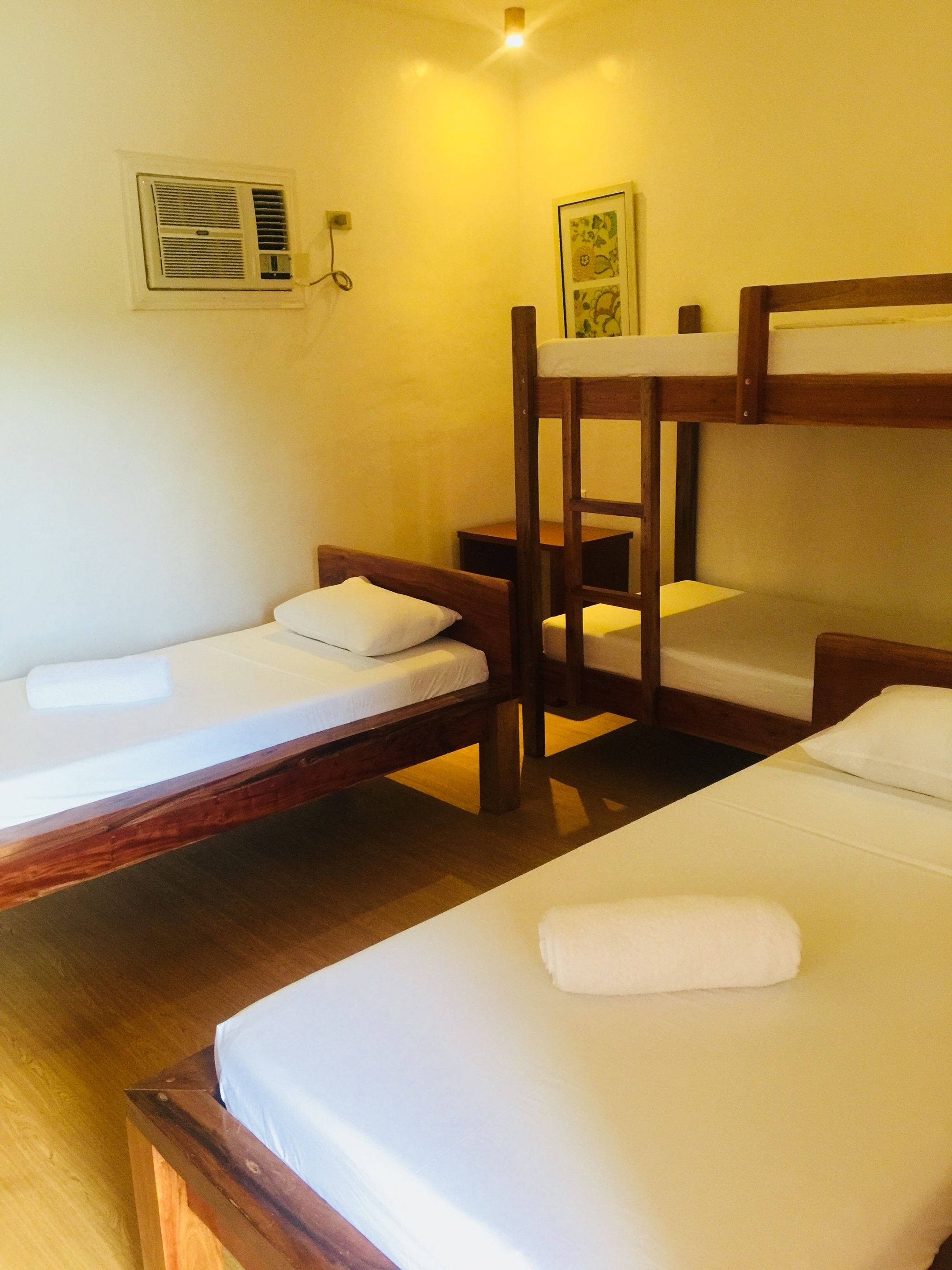 A dormitory room with bunk beds and a single bed, equipped with a heater and a picture on the wall.