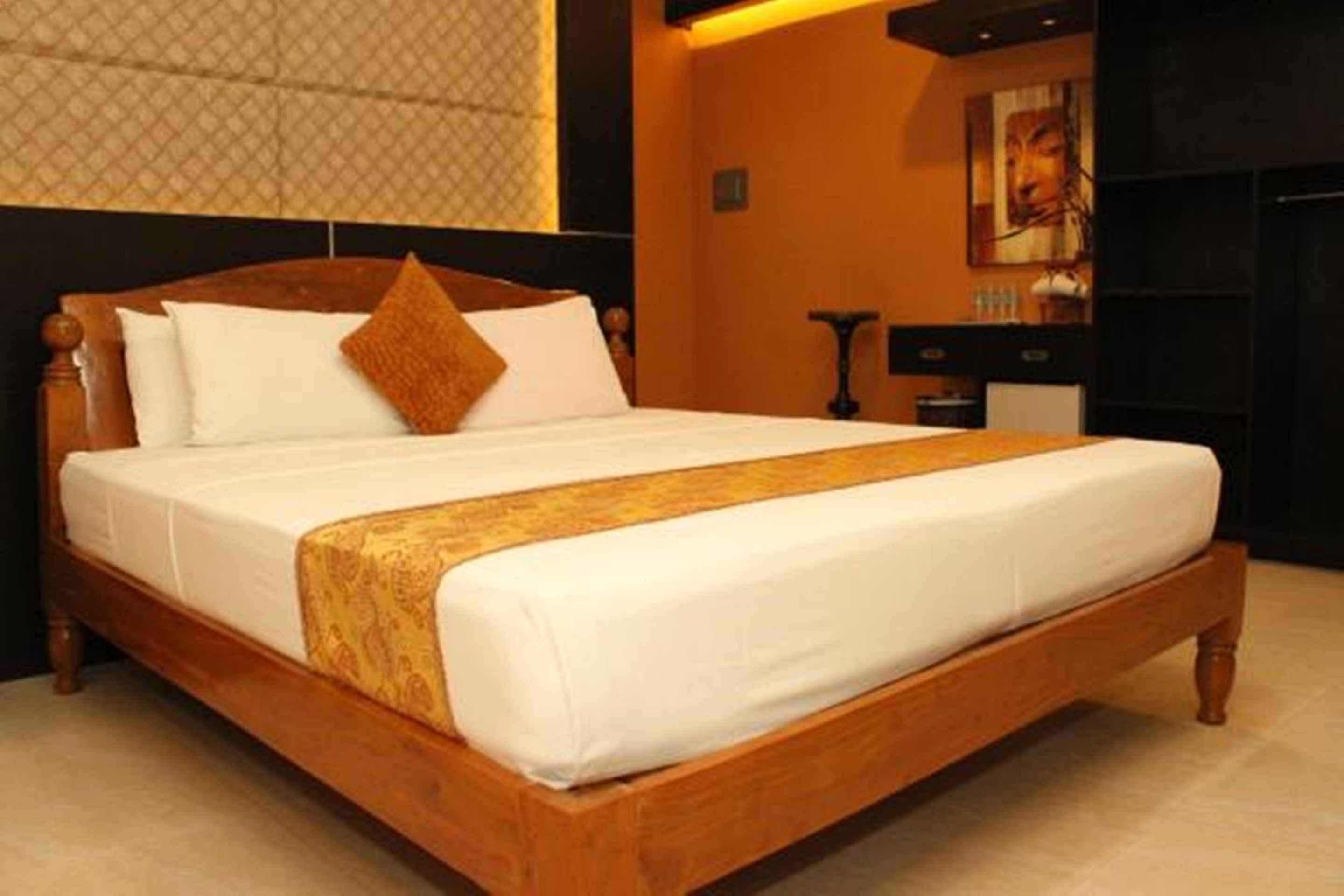 A large bed with a wooden frame, white bedding, and a decorative throw.