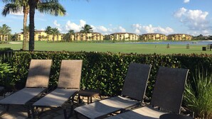 Un resort con vistas a un campo de golf, palmeras y un conjunto de edificios.