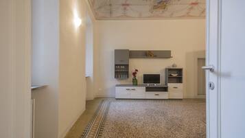 Un pasillo con alfombra estampada, una puerta blanca y un estante de pared con objetos decorativos.