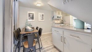 Una cocina moderna con armarios blancos, una mesa de comedor con sillas y un microondas.