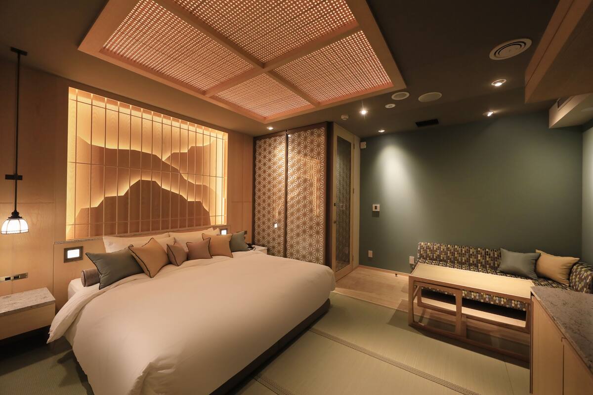A modern bedroom with a large bed, a sofa, and a small table.