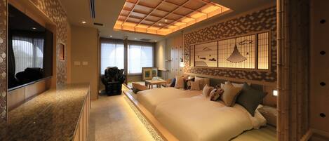 A spacious bedroom with a large bed, a TV, a desk, and a decorative wall.