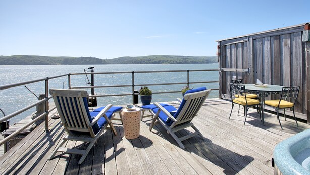 Une terrasse en bois avec deux chaises longues, une table et un jacuzzi.