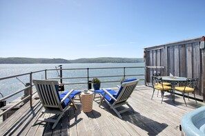 Eine Holzterrasse mit zwei Liegestühlen, einem Tisch und einem Whirlpool.