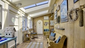 Une pièce chaleureuse avec un plafond en pente, un banc en bois, un fauteuil à bascule et une petite table sur laquelle est posée une nichoir.