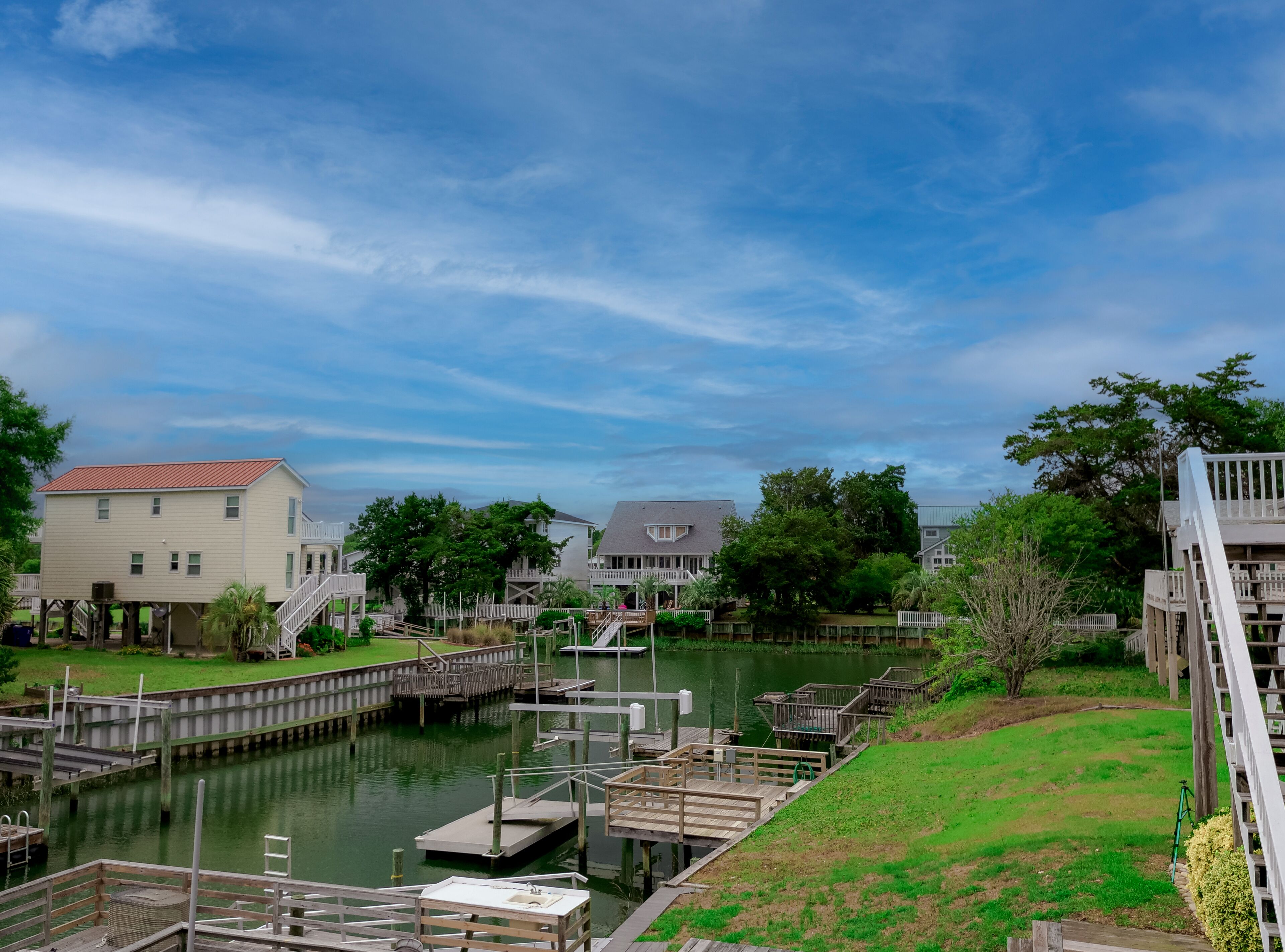 A waterfront property with docked boats, a grassy area, and a building with a red roof.