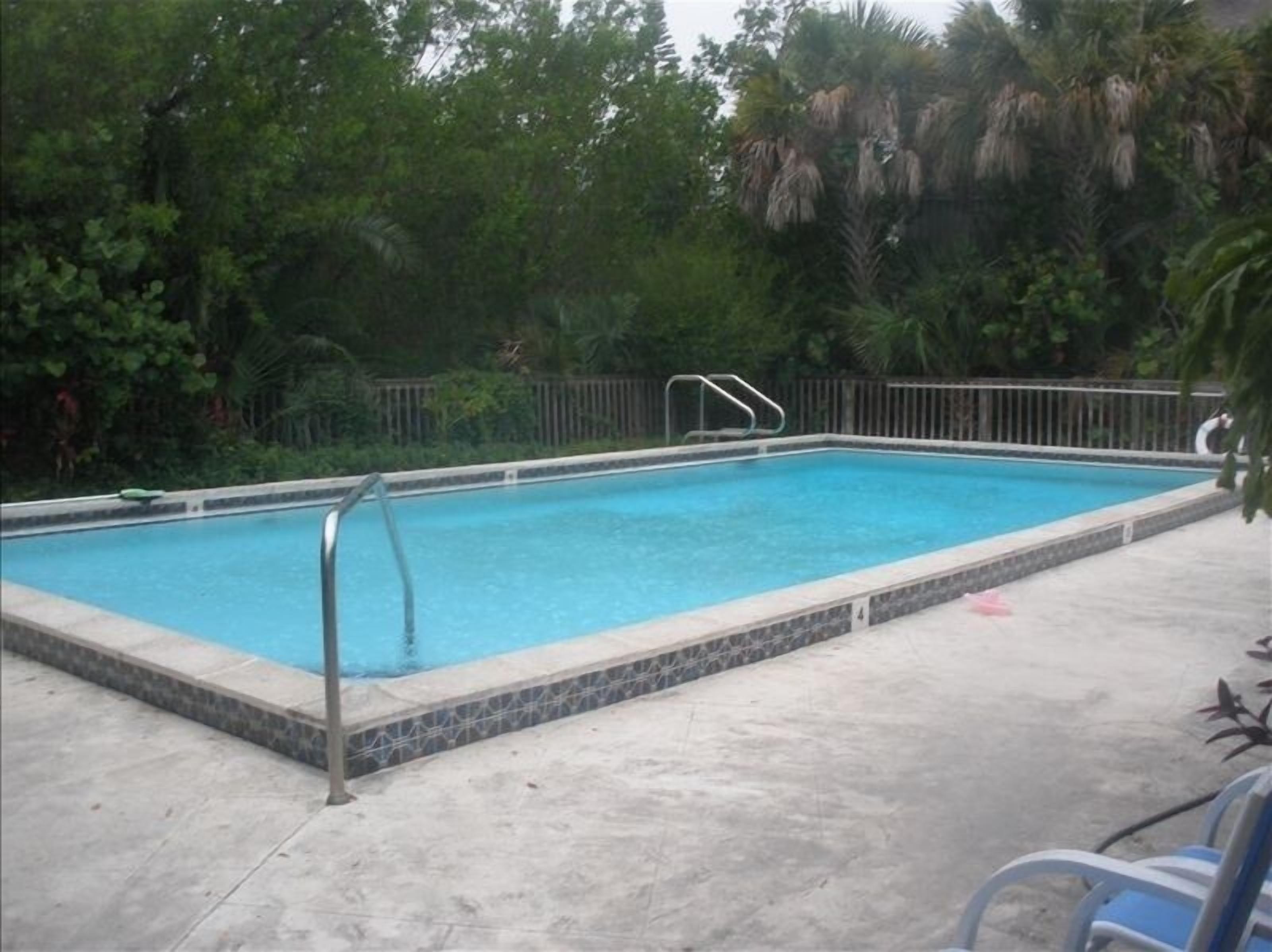 Piscina retangular com borda azulejada, rodeada por um deck de concreto.