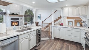 A spacious kitchen with a fireplace, white cabinetry, and a large skylight.