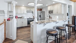 A kitchen with white cabinetry, a central island with stools, a wooden ceiling, and recessed lighting.