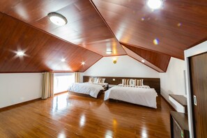 A spacious attic bedroom with wooden flooring, two beds, and a sloped ceiling with recessed lighting. - King Villa (Xuan Huong - Da Lat)