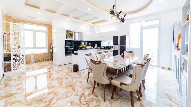 A spacious dining area with a marble floor, a central island, and a modern chandelier. - King Villa (Xuan Huong - Da Lat)