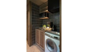 A compact kitchen with a built-in washer and dryer, a small countertop, and a dark backsplash.
