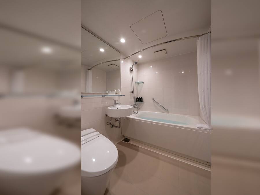 A modern bathroom with a toilet, sink, and bathtub.