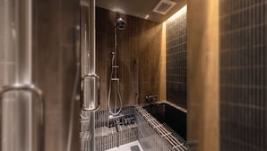 A modern bathroom with a glass-enclosed shower, a large mirror, and a tiled wall.