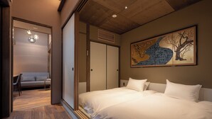 A modern hotel room with a large bed, a sofa, and a sliding door closet.