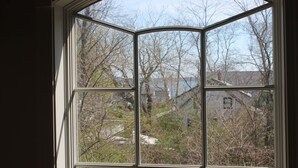 A bay window with a view of a residential area, including trees and houses. - Walk to the  beach and Kayak at Black Point, Niantic, Ct. (Niantic)