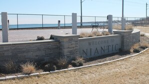 A stone wall with a welcome sign, a bench, and a view of the water. - Walk to the  beach and Kayak at Black Point, Niantic, Ct. (Niantic)