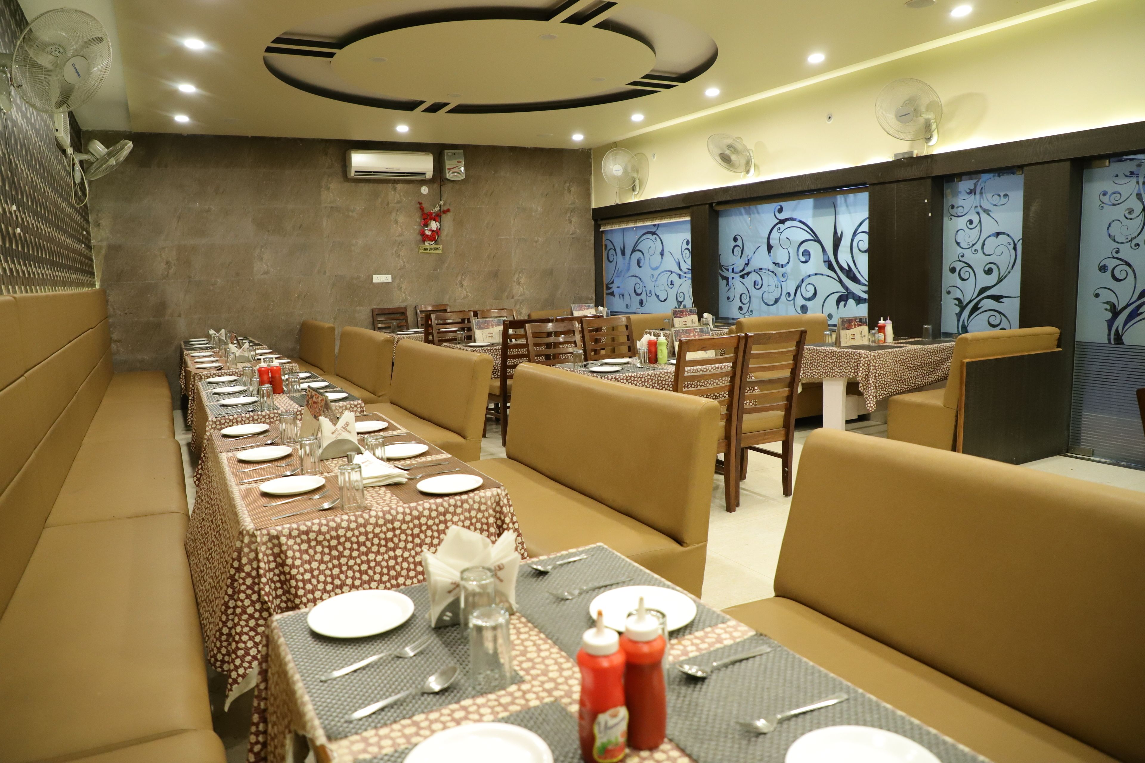 A restaurant with multiple dining tables set with plates, cutlery, and condiments.