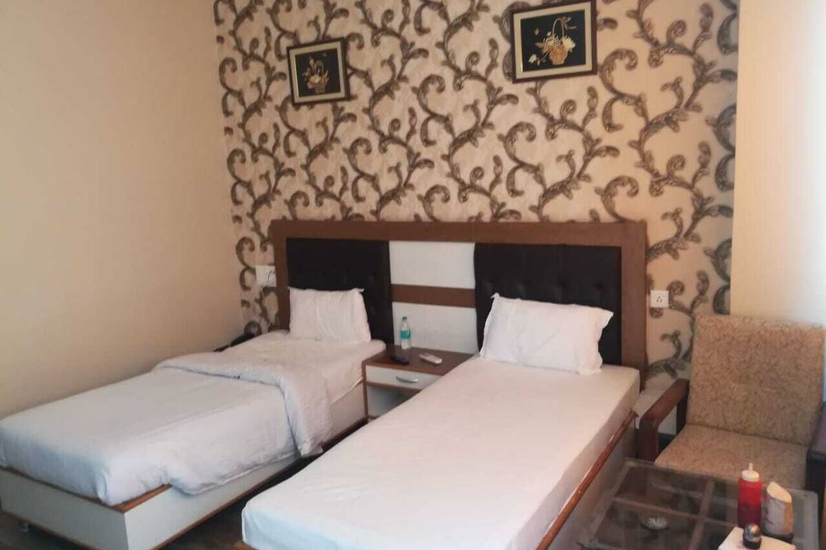 Ein Hotelzimmer mit zwei Einzelbetten, einem kleinen Tisch mit Stuhl und einer Wanddekoration.