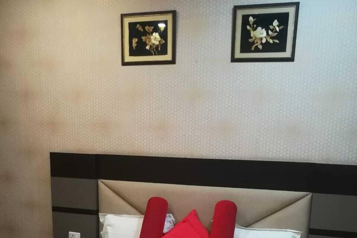 Ein ordentlich bezogenes Bett mit einer roten und weißen Tagesdecke, zwei roten Kissen und einer dekorativen Schwanen-Handtuch-Arrangement.