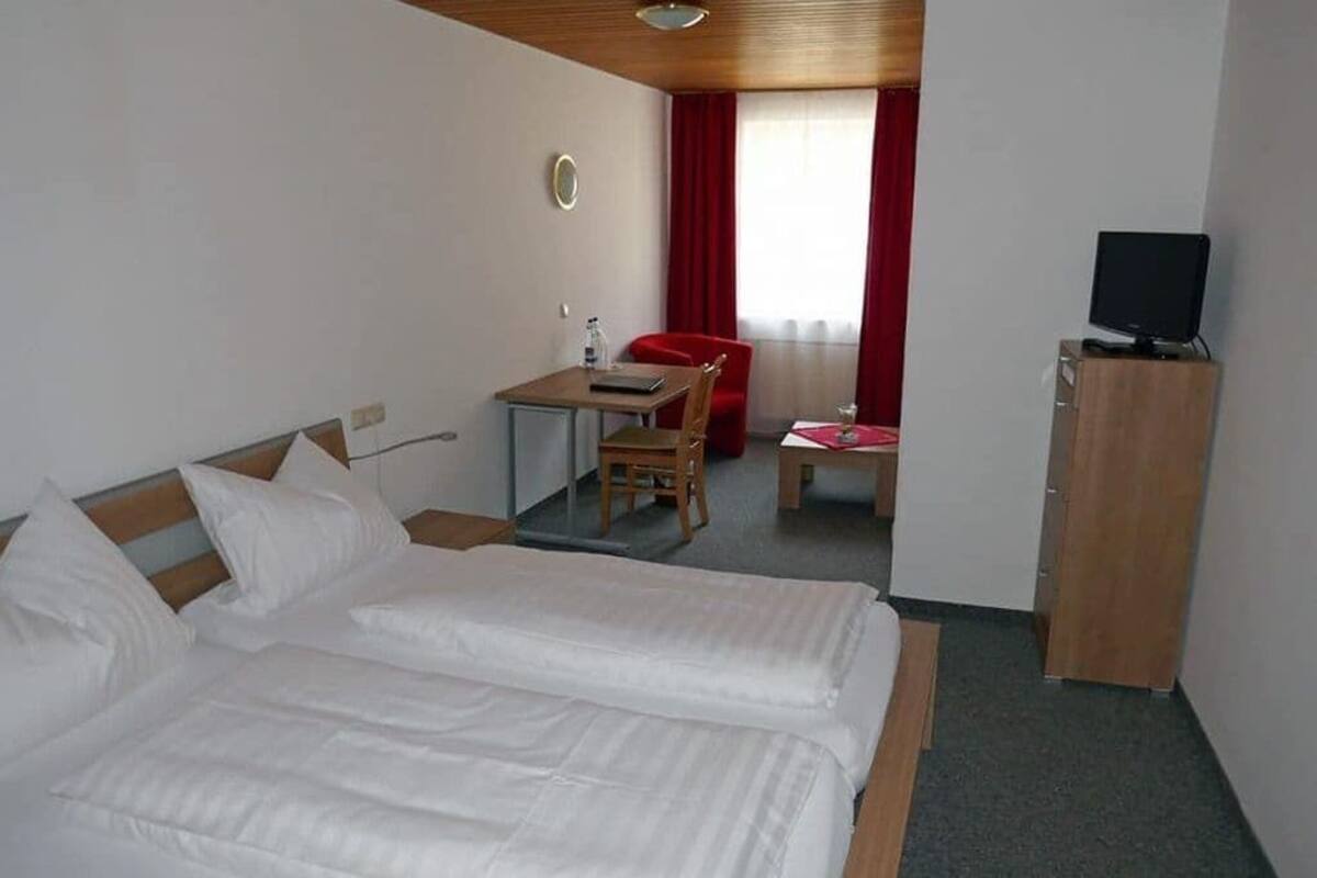 Een hotelkamer met een bed, een bureau, een stoel, een televisie en een kledingkast.