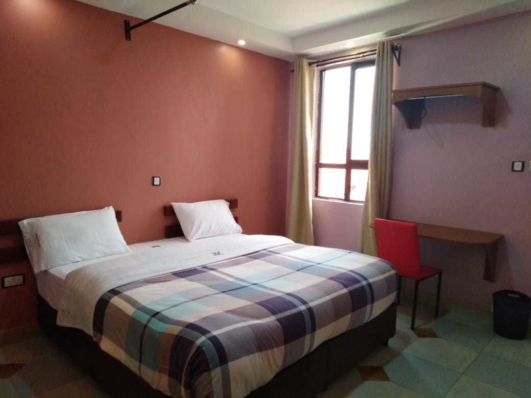 Un dormitorio con cama, una silla, una ventana y una estantería.