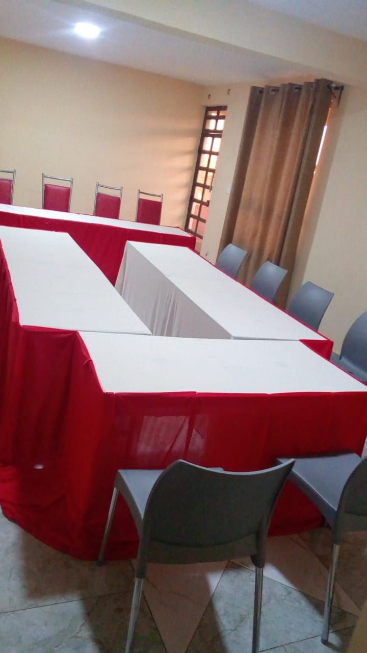 Un salón de conferencias con una larga mesa cubierta de rojo, rodeada de sillas.