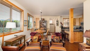 A cozy living room with a fireplace, wooden furniture, and a dining area with a table and chairs. - Luxurious, affordable condo one mile from downtown (Ketchum)