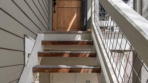 A wooden staircase with a metal railing leading to a door. - Luxurious, affordable condo one mile from downtown (Ketchum)