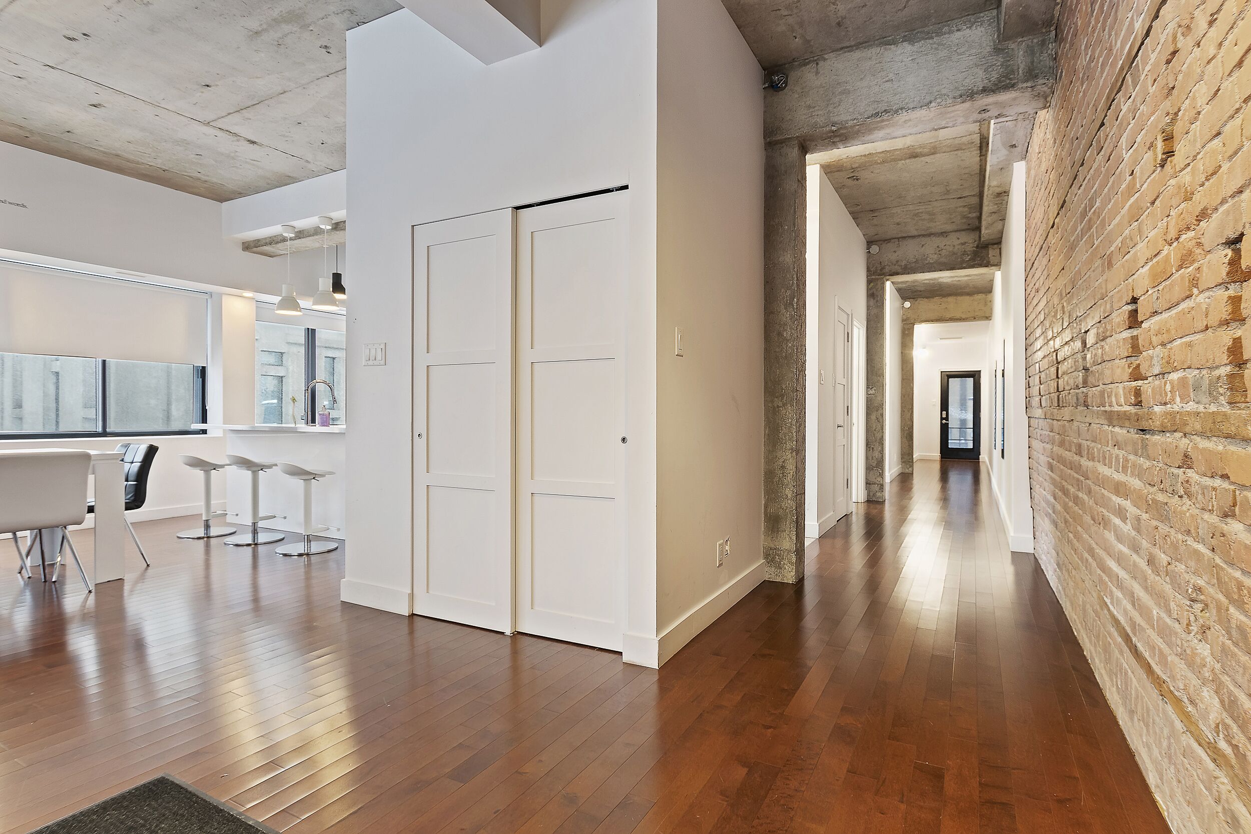 A modern interior with a kitchen area, white walls, and a brick accent wall.