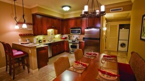 A modern kitchen with wooden cabinets, a central island, stainless steel appliances, and a dining area set for six. -  NAPAS GEM!  1 BEDROOM (Napa)