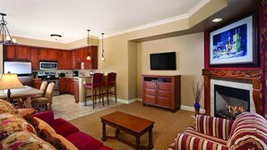 A modern living room with a sofa, a coffee table, and a fireplace. There is a kitchen area with a microwave and a dining table. -  NAPAS GEM!  1 BEDROOM (Napa)