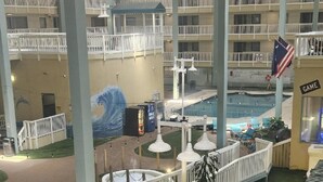 An indoor pool area with multiple levels of balconies, a mural of a wave, and a 'Game' sign indicating a gaming area.