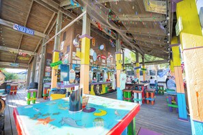 An outdoor restaurant with colorful tables and chairs, a wooden deck, and various signs and decorations. - Beautiful Villa by the Ocean!  A perfect getaway! (Hilton Head Island)