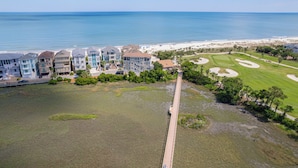 An aerial view of a coastal hotel with multiple buildings, a golf course, and a beach.