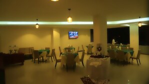 A spacious dining area with multiple tables and chairs, a television mounted on the wall, and pendant lighting. - Wynn Hotel - Bahir Dar (Bahir Dar)